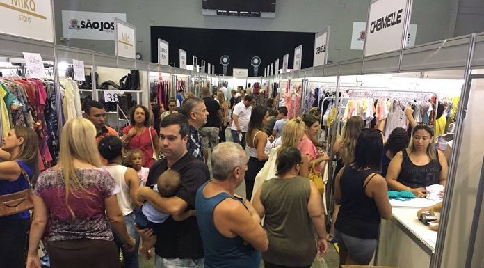 Muitas pessoas circulando em um corredor entre stands de lojas