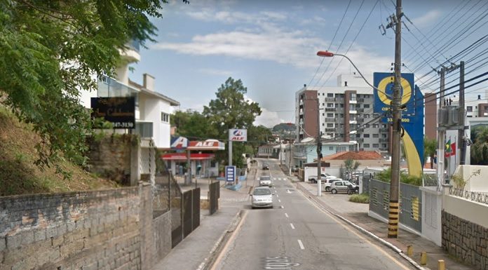 vista central da rua, com carros vindo ao fundo e comércios em volta num dia ensolarado