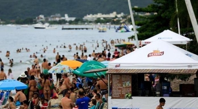 aglomeração de banhistas na areia da praia de canasvieiras ao lado de uma barraca de bebidas