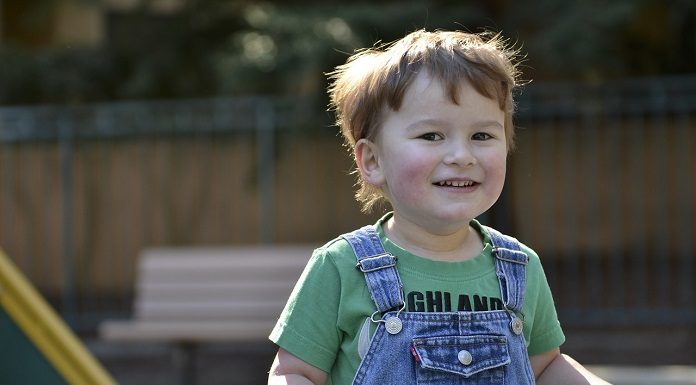 menino brinca sorridente em um parquinho