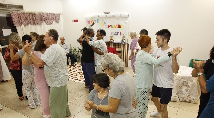 pessoas, a maioria idosas, dançando de pijama em um salão