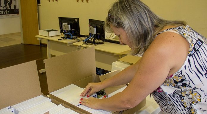 mulher confere dezenas de carnês de iptu em caixas de papelão