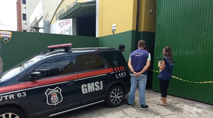 viatura da guarda municipal estacionada em frente ao portão da empresa com fiscais da susp de colete ao lado