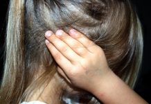 menina vista de lado com as mãos nos ouvidos; não é possível ver seu rosto; SC tem 10 casos diários de violência sexual contra menores