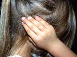 menina vista de lado com as mãos nos ouvidos; não é possível ver seu rosto; SC tem 10 casos diários de violência sexual contra menores