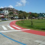 pista de corrida sem ninguém no parque de coqueiros e construções ao fundo