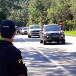 policial no ascostamento de rodovia no meio da mata observa carros passando