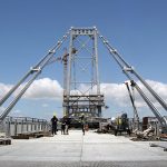 foto do chão gradeado da ponte, da torre e de das barras de olhas que sustentam a estrutura dos lados