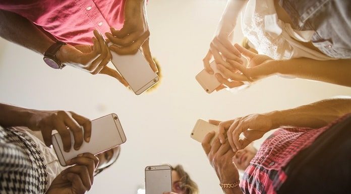 cinco pessoas em roda usando celulares vistas de baixo