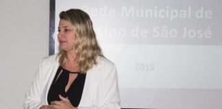 lilian em pé discursando com uma projeção de slide atrás