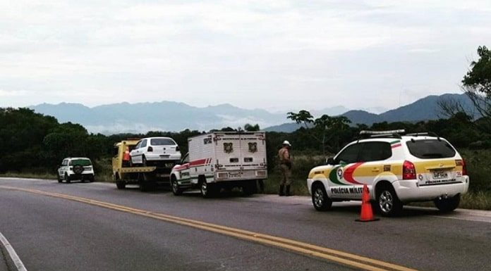 carro gol antigo sobre guincho no acostamento com outras viaturas do igp, iml e pm em volta