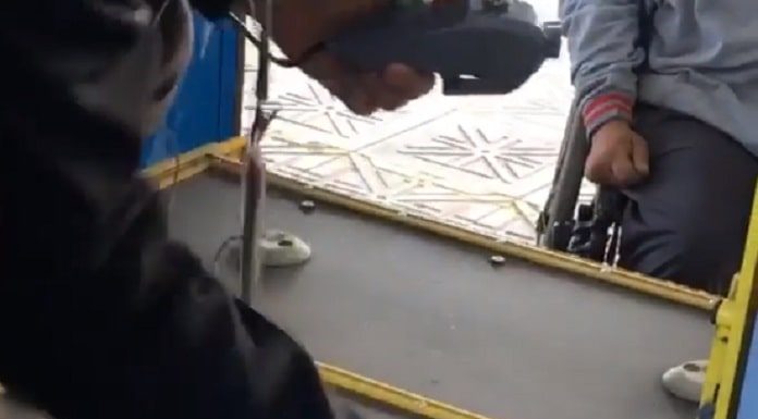 homem dentro do ônibus mexe com ferramenta na plataforma do elevador enquanto homem em cadeira de rodas espera no lado de fora