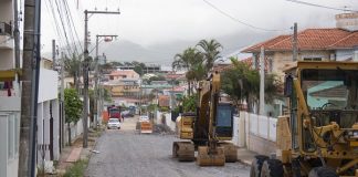 retroescavadeira e máquina de terraplanagem estacionadas em rua com cobertura de britas, em obras