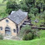 usina vista de cima, com canos indo à casa de força e riacho ao lado