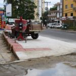 obra da calçada, com altura maior que as vagas de comércio, betoneira sobre a calçada e comércios em volta