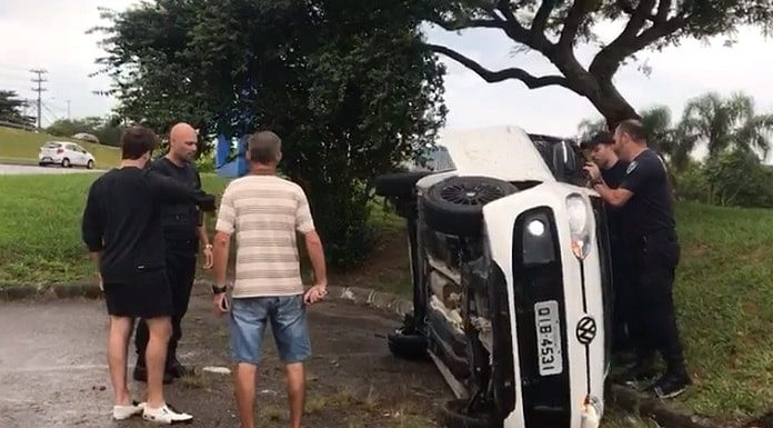 carro vw up capotado de lado com homens em volta