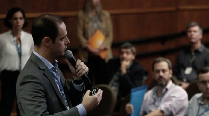 cleicio fala ao microfone em pé em frente a pessoas sentadas em auditório