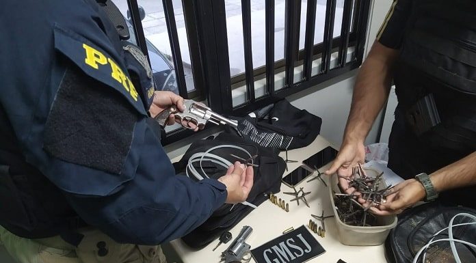 mesa com os materiais apreendidos e um agente da prf e outro da gmsj ao lado mexendo nos objetos