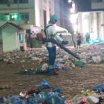 homem com uniforme da comcap e soprador limpa grande área cheia de lixo no centro