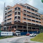 prédio em construção com placa na frente escrita "aemflo nova sede"