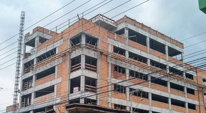 prédio em construção com placa na frente escrita "aemflo nova sede"