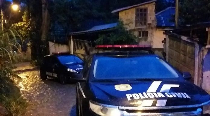 gm edge e ford fiesta da polícia civil estacionados em ladeira estreita molhada de chuva com pequenas casas ao lado; rua em curva; amanhecendo