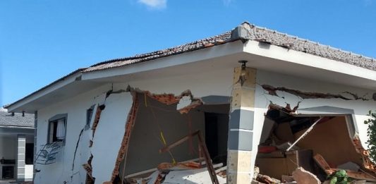 casa com grandes rachaduras e praticamente destruída, com detritos espalhados