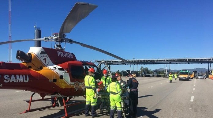 helicóptero taxiado na pista em frente ao pedágio com equipes de resgate em volta