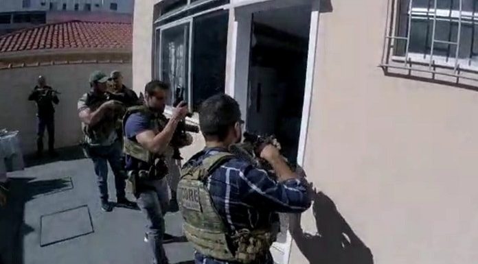 policiais armados com metralhadoras em posição de invasão na porta de uma kitnet