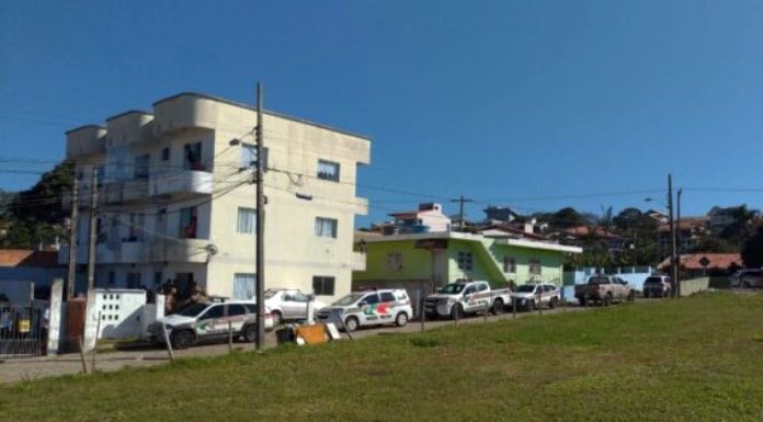 viaturas da pm estacionadas em servidão ao lado de grande terreno baldio em frente ao pequeno prédio de três andares