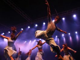 homens e mulheres apresentando uma dança em um palco