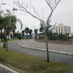 curva do calçadão da beira-mar de são josé junto com ciclovia; não há ninguém; dia nublado; árvores ao longo da orla; prédios ao fundo