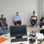 Na foto se vê sete pessoas sentadas em cadeiras e em círculo, elas estão afastadas e usam máscaras. A reunião da defensoria pública com a prefeitura e moradores das ocupações da Boa Vista e Vale das Palmeiras, em São José, discutiu a situação dos moradores das localidades.