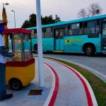 ônibus de transporte intermuicipal da empresa estrela saindo sda ponte herc´pilio luz e na calçada em primeiro plano pipoqueiro usando máscara com carrinho de pipoca