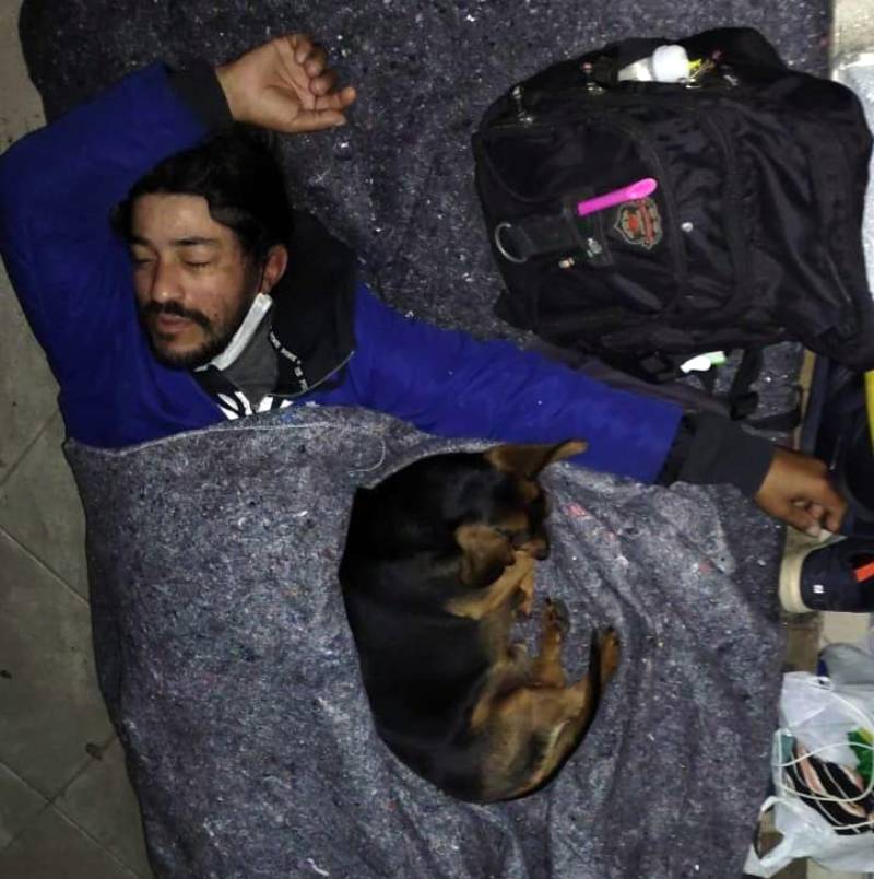 homem dorme com cachorro em cama no chão - Moradores de rua são acolhidos em hotel em Florianópolis
