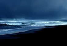 foto de uma praia no início da noite com mar agitado e muitas nuvens - previsão do tempo de chuva em sc